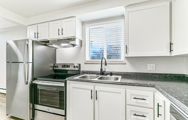 Contemporary kitchen featuring sleek stainless steel appliances, elegant white cabinetry, and a sunlit window view.