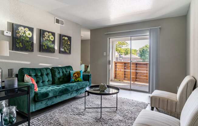 a living room with a green couch and a sliding glass door