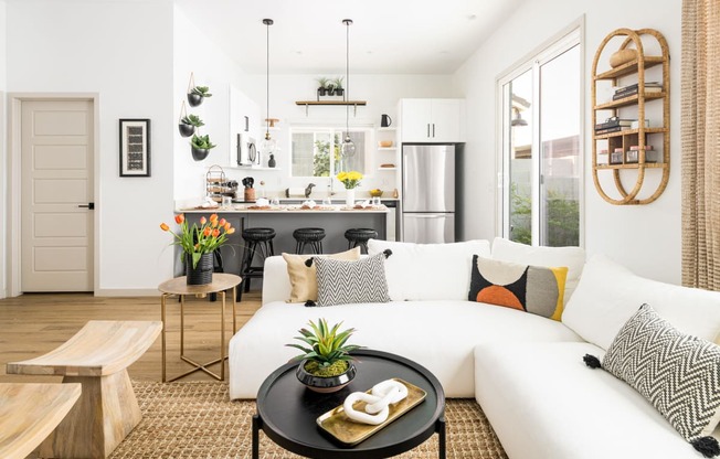 a living room with a white couch and a kitchen in the background