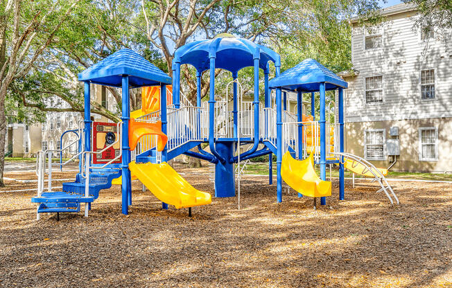 Playground with multiple slides, stairs surrounded by native landscaping and building exterior