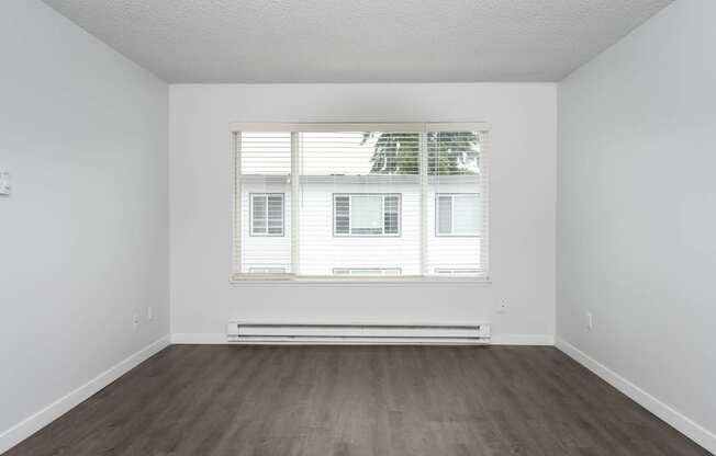 an empty room with wood floors and a window