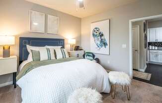 A bedroom with a large bed and a painting of an owl on the wall.