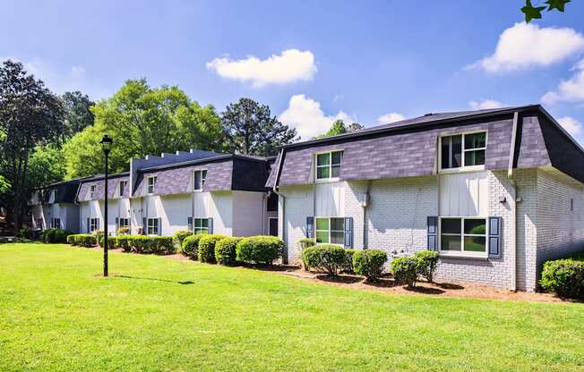 A white house with a grey roof and a green lawn in front.