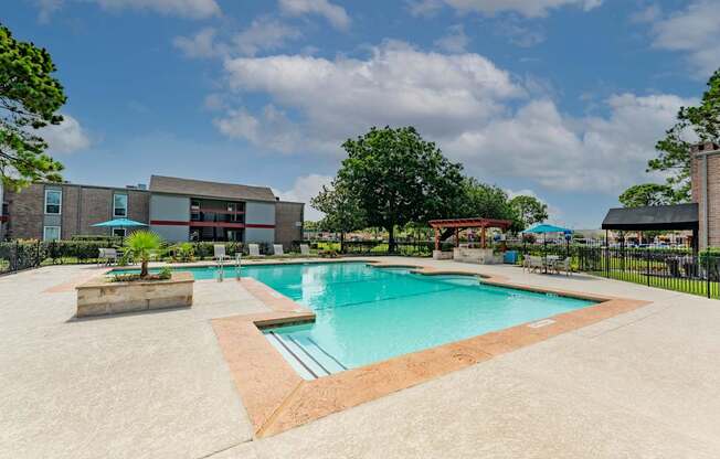 A large outdoor swimming pool with a concrete deck and a building in the background.