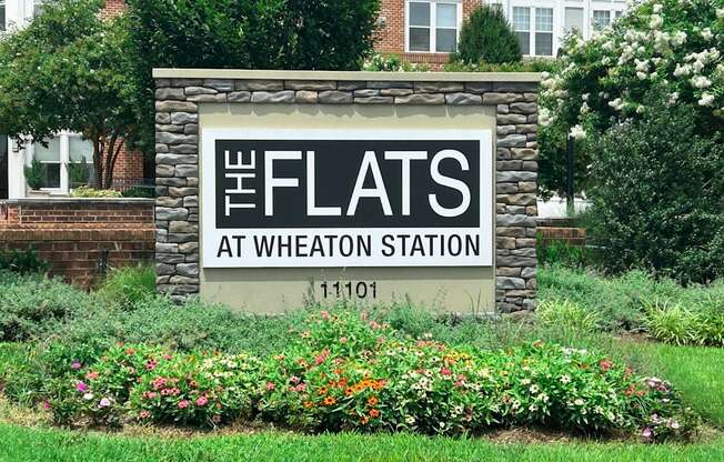 A sign that says "The Flats at Wheaton Station" in front of a building.