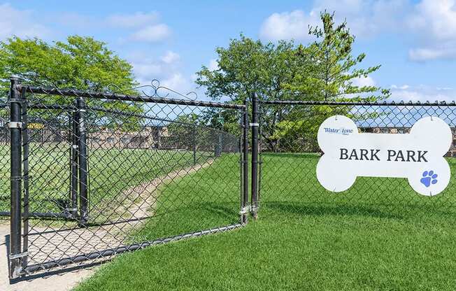 a park with a fence and a sign that reads bark park