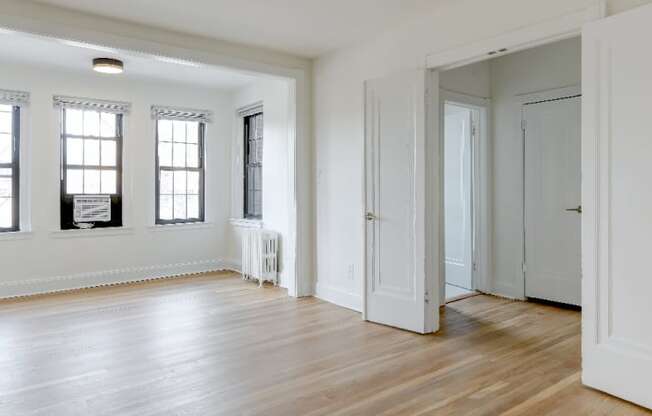 vacant living area with hard wood flooring and large windows at the dahlia apartments washington dc