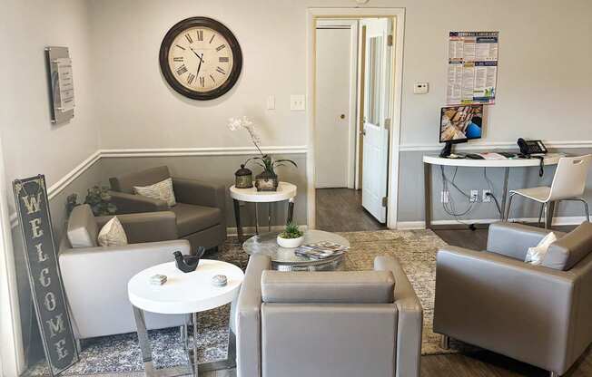 A living room with a grey sofa, a white coffee table, and a large clock on the wall.