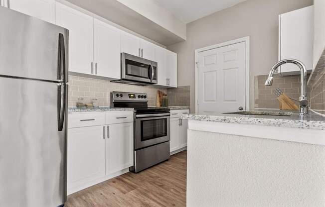 A kitchen with white cabinets and a stainless steel refrigerator.