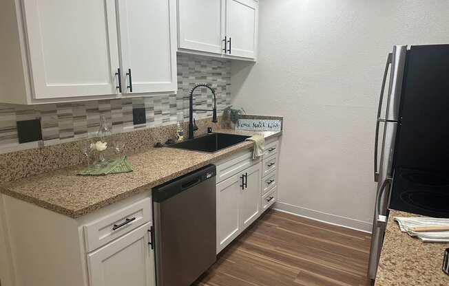 A kitchen with white cabinets and a granite countertop at Willow Tree Apartments, California, 90505