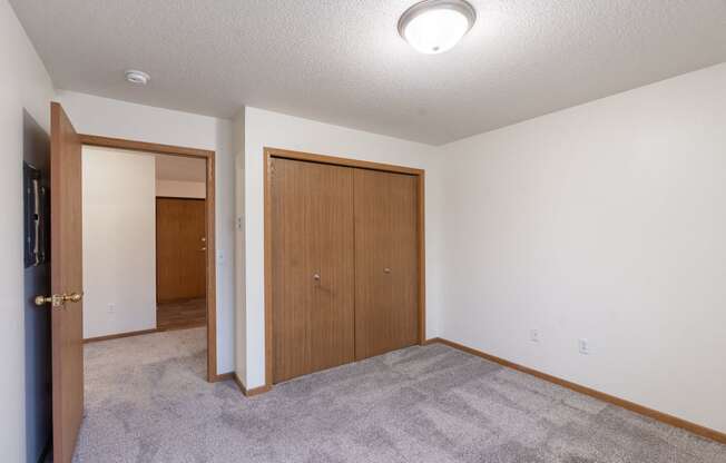 an empty living room with a door to a bedroom and a closet. Fargo, ND Oxford Apartments