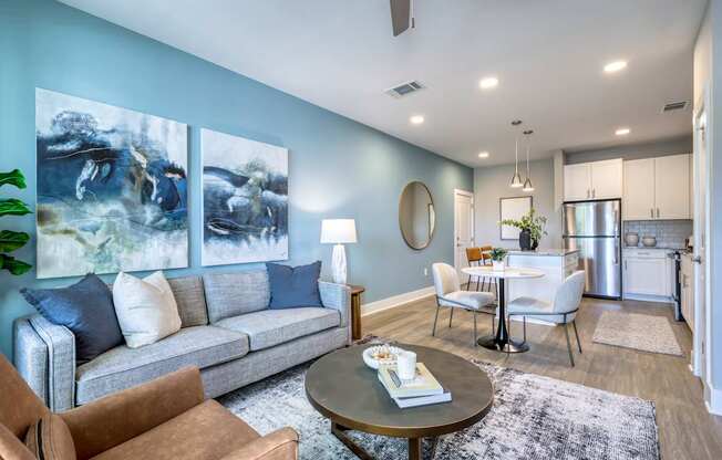 A living room with a grey couch, a coffee table, and a painting on the wall.