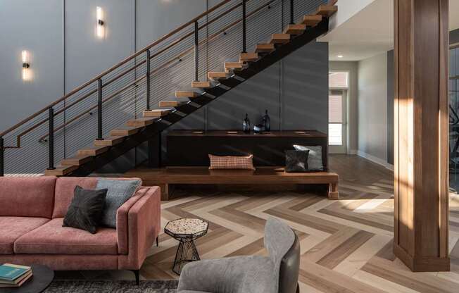 A living room with a couch, a chair, a coffee table, and a staircase.