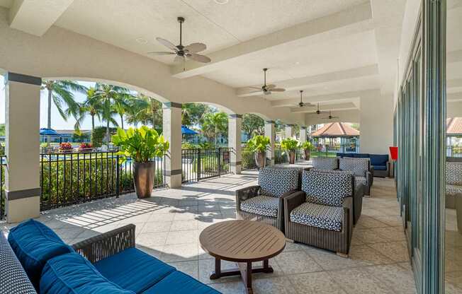 An outdoor lounge area that is covered with a ceiling and paddle fans