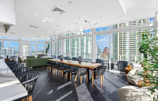 A large conference room with a long table and chairs, a green sofa, and a view of the city through the windows.