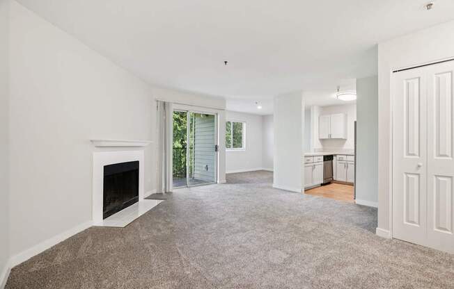 A spacious living room with a fireplace and carpeted floor.