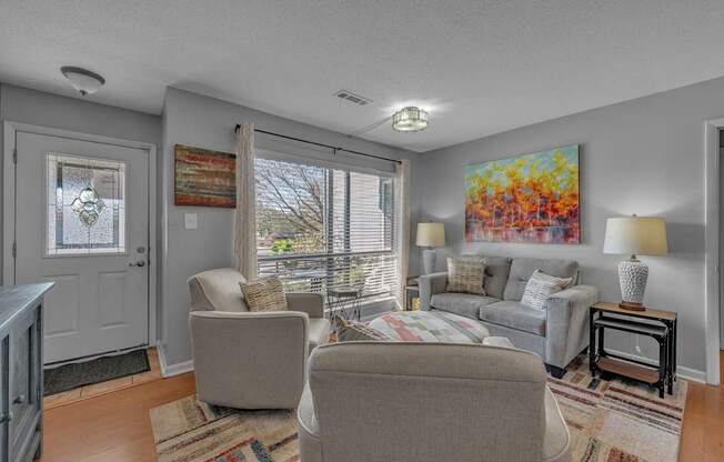 A living room with a grey couch and a painting on the wall.