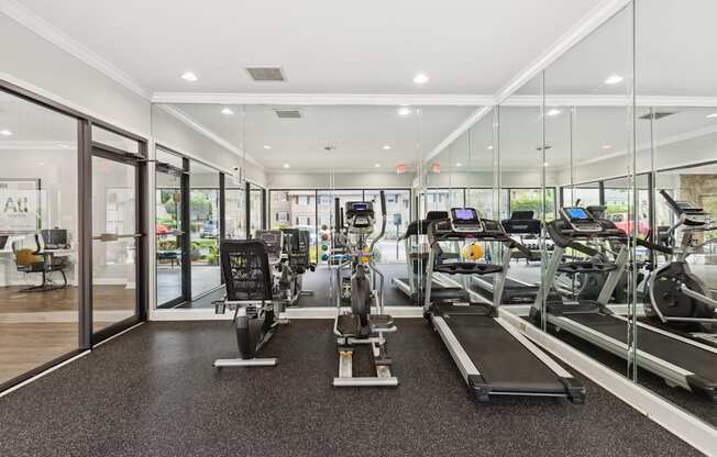 a gym with cardio equipment and glass walls