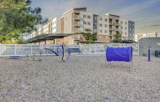 a playground with a blue slide and swing set in front of an apartment building