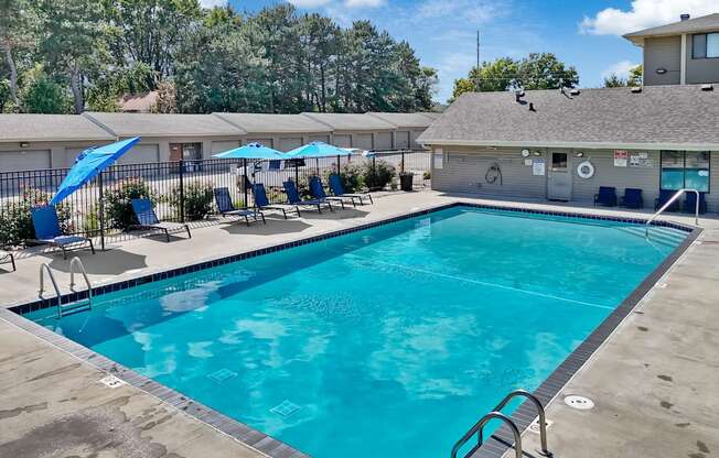 A large swimming pool with a diving board and lounge chairs.