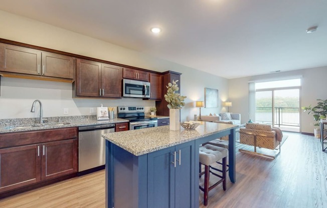 a kitchen with a large island and a living room in the background