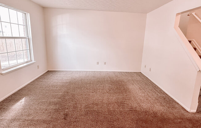 an empty room with a carpeted floor and a window