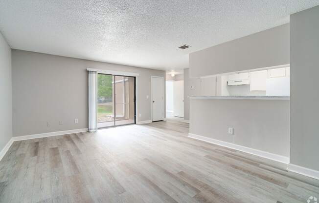 an empty living room and kitchen with a sliding glass door to a patio