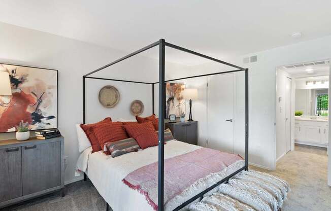 A bedroom with a four poster bed and a grey cabinet.