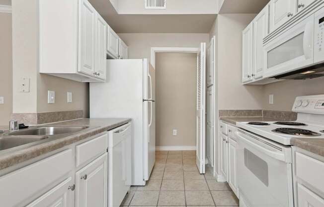 Edinburgh kitchen with white appliances and cabinets at Encore at Buckingham Apartments in Richardson, TX