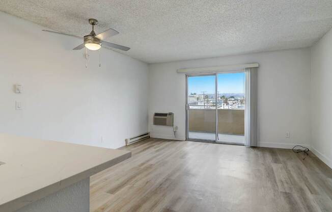 A room with a ceiling fan and sliding glass doors.