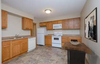 a kitchen with white appliances and wooden cabinets. Fargo, ND Birchwood 2 Apartments