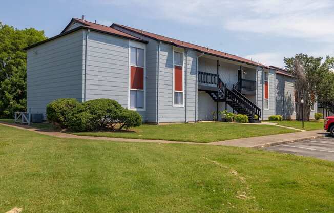 a blue building with red and white doors and a lawn