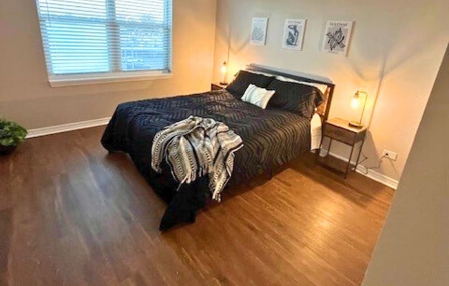 A bedroom with a bed, nightstand, and pictures on the wall.