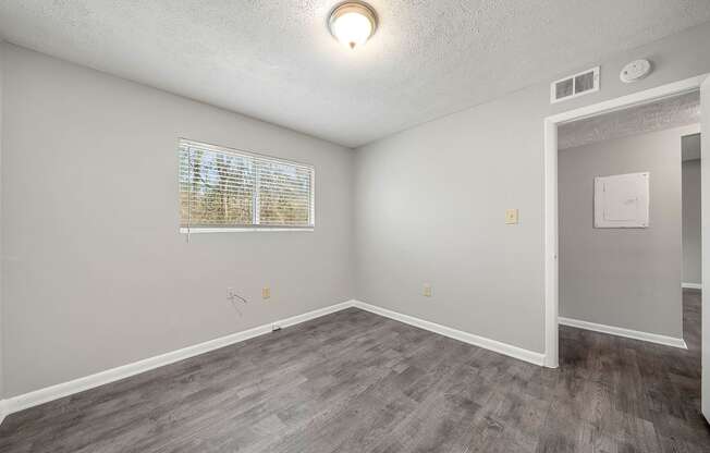 an empty living room with white walls and wood flooring and a window