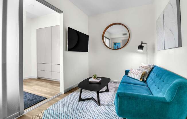 a living room with a blue couch and a round mirror on the wall