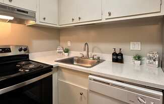 a kitchen with white cabinets and a sink and a stove