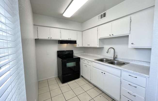 A kitchen with white cabinets and a black oven.