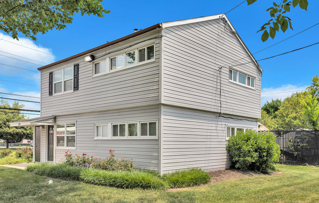 the back of a gray house with white siding and a yard with grass