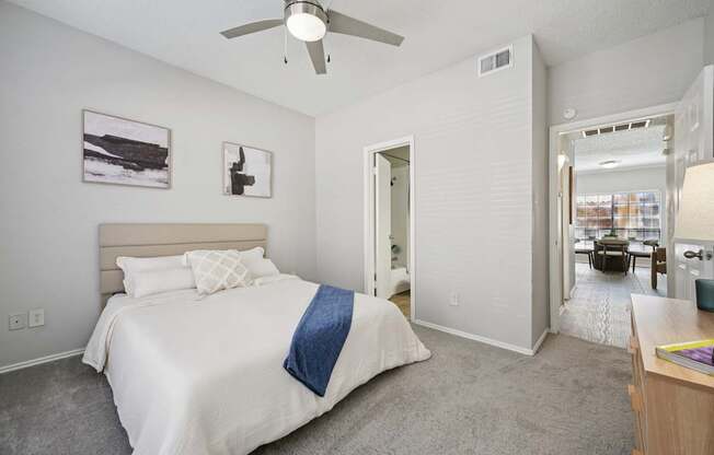 A bedroom with a bed, a ceiling fan, and a picture on the wall.