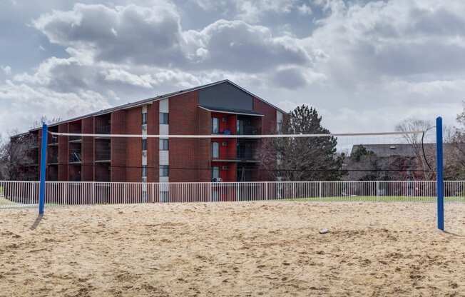 a building on a beach with a volleyball court in front of it