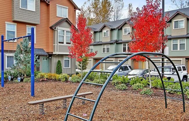 Kenmore WA Apartments - Northshore Townhomes - Outdoor Playground with Metal Bars, Swings, and Surrounding Trees