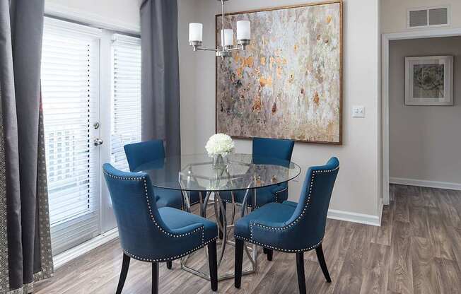 A dining room with a glass table and blue chairs.