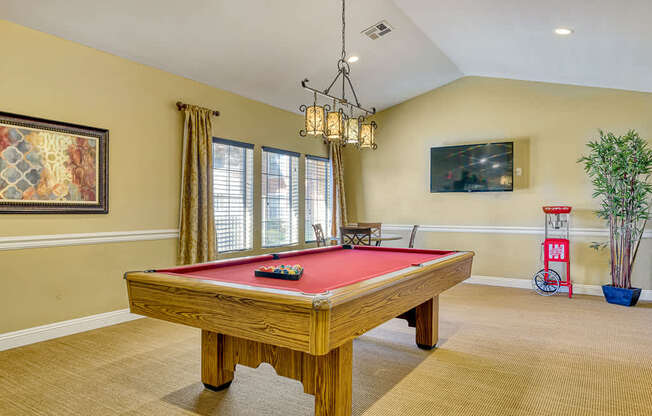a game room with a red pool table and a chandelier