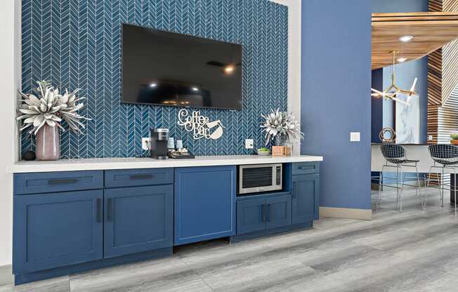 Clubhouse kitchen with blue cabinets and a tv on the wall