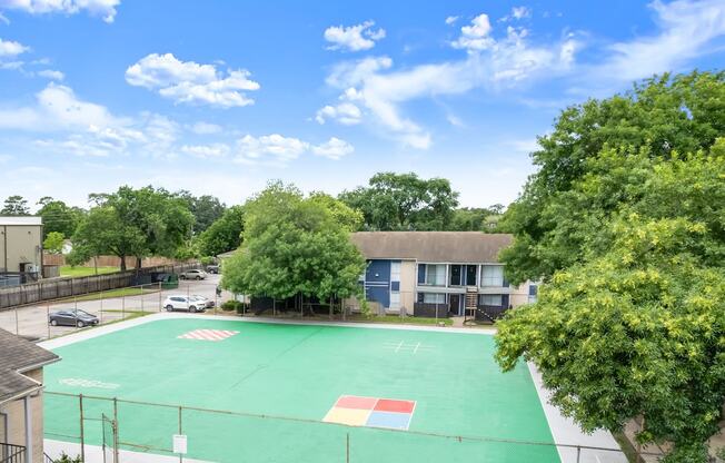 a basketball court in front of a building with trees