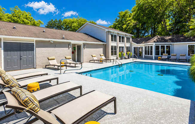 A poolside area with sun loungers and a building in the background.