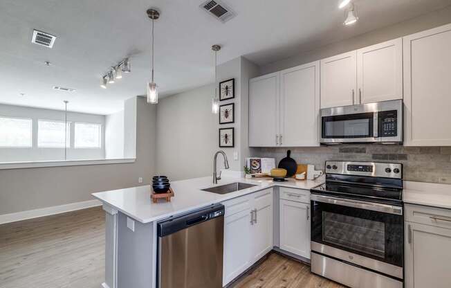 A modern kitchen with white cabinets and stainless steel appliances.