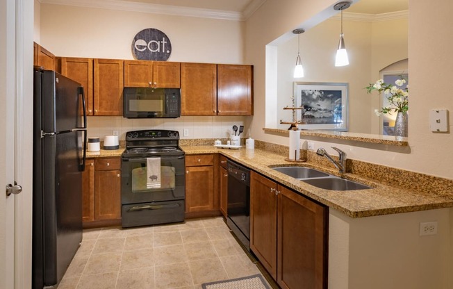 U shaped kitchen with black appliances and dark brown cabinets. Granite counter tops throughout the kitchen.