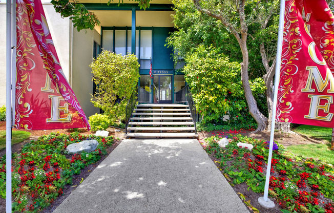 a path leading up to a building with flowers and trees at Casa Del Amo Apartments, Torrance, CA