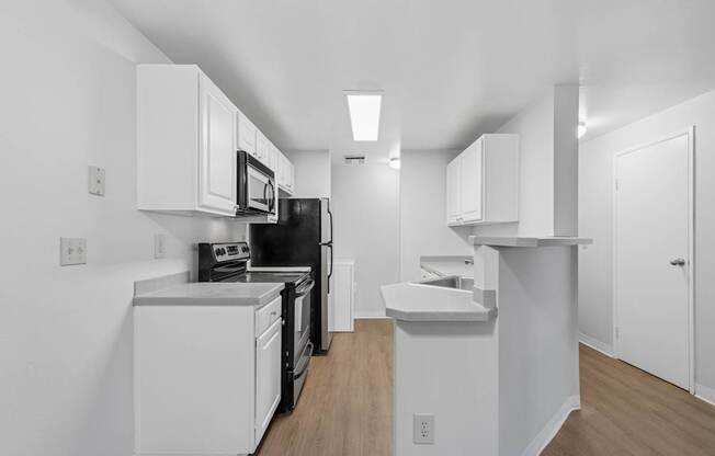 A kitchen with white cabinets and black appliances.